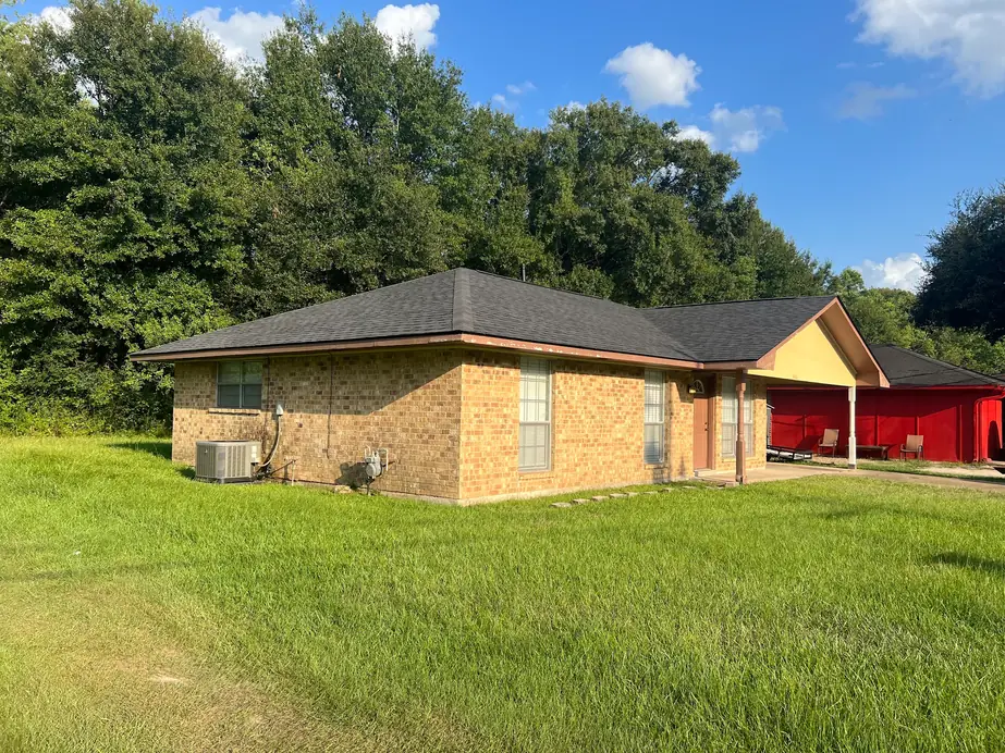Brick home with a new dark shingle hip roof under a clear blue sky