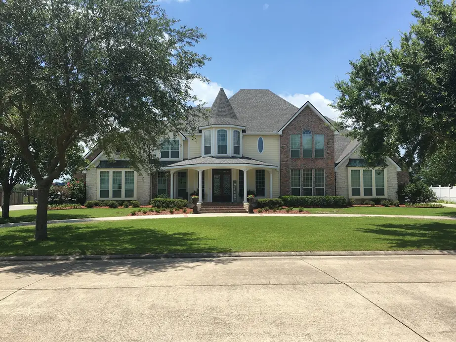 Two-storey Baton Rouge home with a turret under a finished gray shingle roof
